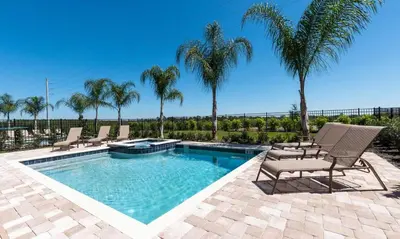 a swimming pool with chairs and palm trees at 5 Star Villa on Orlando’s most Exclusive Encore Resort at Reunion Orlando Villa 4355 in Orlando