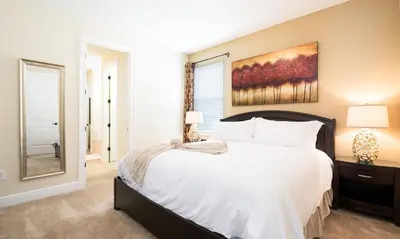 a bedroom with a large bed and a painting on the wall at 5 Star Villa on Orlando’s most Exclusive Encore Resort at Reunion Orlando Villa 4355 in Orlando
