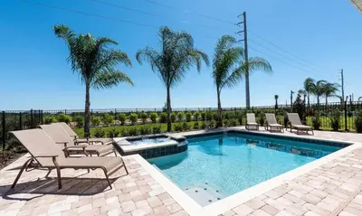 a swimming pool with chairs and palm trees at 5 Star Villa on Orlando’s most Exclusive Encore Resort at Reunion Orlando Villa 4355 in Orlando