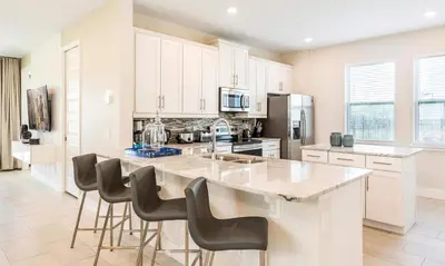 a kitchen with white cabinets and a large island with bar stools at 5 Star Villa on Orlando’s most Exclusive Encore Resort at Reunion Orlando Villa 4507 in Orlando