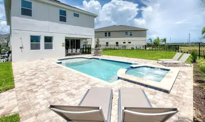 a swimming pool with two chairs and a house at 5 Star Villa on Orlando’s most Exclusive Encore Resort at Reunion Orlando Villa 4507 in Orlando
