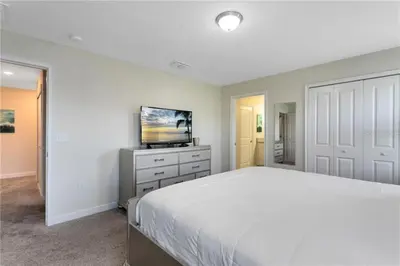 a white bedroom with a bed and a tv at Luxury Townhome on Storey Lake Resort Orlando Townhome 5523 in Kissimmee