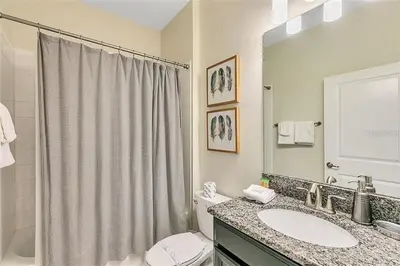 a bathroom with a sink and a toilet and a mirror at You Will Love this 5 Star Villa located on Storey Lake Resort Orlando villa 5492 in Kissimmee