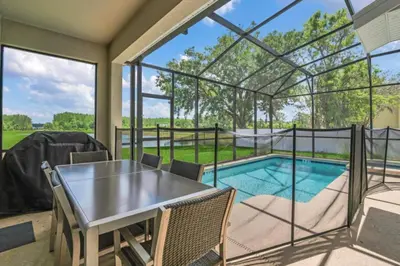 a patio with a table and chairs and a swimming pool at Escape to a 5 Bedroom Villa in Paradise 6316 in Kissimmee