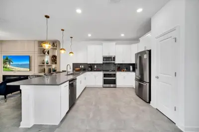 a kitchen with white cabinets and a black refrigerator at Family-Friendly Villa with 9 Bedrooms 6317 in Kissimmee