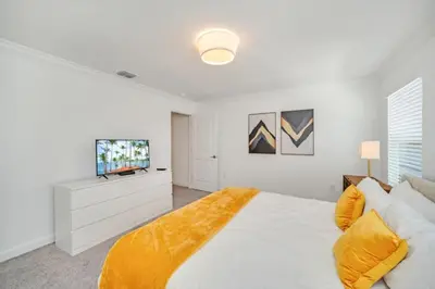 a white bedroom with a bed and a tv at Cozy 4 Bedroom Urban Oasis 6326 in Kissimmee