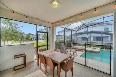 a patio with a table and chairs and a swimming pool at 6 Bedroom Villa with Tennis Court Gym 6332 in Kissimmee