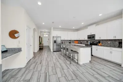 a kitchen with white cabinets and a wooden floor at 6 Bedroom Villa with Tennis Court Gym 6332 in Kissimmee