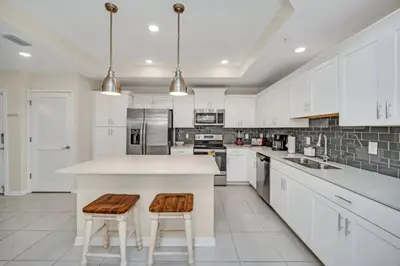 a kitchen with white cabinets and a large island with stools at Chic Urban Oasis with 3 Bedrooms 6333 in Kissimmee