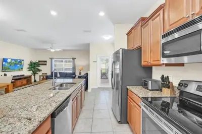 a kitchen with stainless steel appliances and a living room at Spacious 5 Bedroom Villa for Families 6337 in Kissimmee