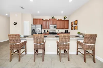 a kitchen with wooden cabinets and a counter with chairs at Tranquil Villa Retreat with Mountain Views 6338 in Kissimmee