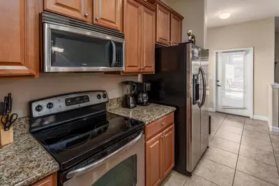 a kitchen with stainless steel appliances and wooden cabinets at Rent this Luxury 5 Star Townhome on Paradise Palms Resort Orlando Townhome 6299 in Kissimmee