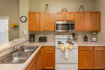 a kitchen with wooden cabinets and a white appliance at Orlando 6424 Townhome: Family Fun Close to Disney in Kissimmee