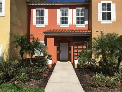 a orange house with a door and a sidewalk at Luxury Orlando Townhome 6425 - Emerald Island Resort Stay in Kissimmee