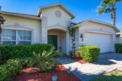 a house with a palm tree in front of it at Orlando Villa 6426: Cumbrian Lakes Pool Spa Retreat in Kissimmee