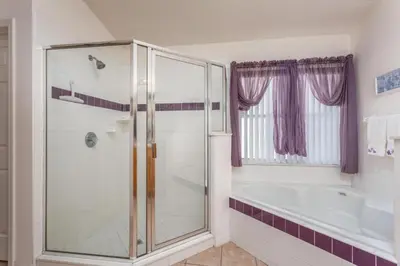 a bathroom with a shower and a tub at Orlando Villa 6426: Cumbrian Lakes Pool Spa Retreat in Kissimmee