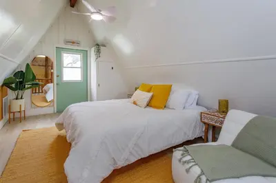 a attic bedroom with two beds and a chair at Orlando Home 6430: Purpose-Driven A-Frame Vacation Home in Clermont