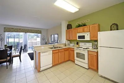 a kitchen with wooden cabinets and a white refrigerator at Orlando Townhome 6436: Family Fun Near Disney World in Orlando