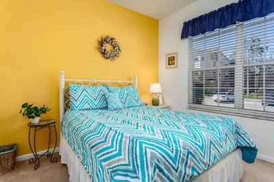 a bedroom with a bed with a blue and white comforter at 5-Star Orlando Townhome 6446: Family Fun Awaits in Kissimmee