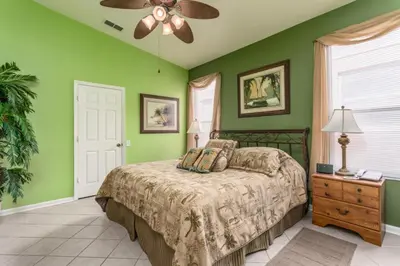 a bedroom with green walls and a bed and a ceiling fan at Orlando Villa 6449: Experience Magic and Relaxation in Kissimmee