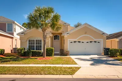a house with a palm tree in front of it at Orlando Villa 6449: Experience Magic and Relaxation in Kissimmee