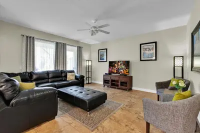 a living room with a black leather couch and a tv at 5-Star Orlando Villa 6452: Family Fun Resort Access in Kissimmee