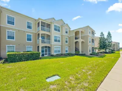 a large apartment building with a green yard at Orlando Condo 6470 - 3BR Family Getaway in Kissimmee