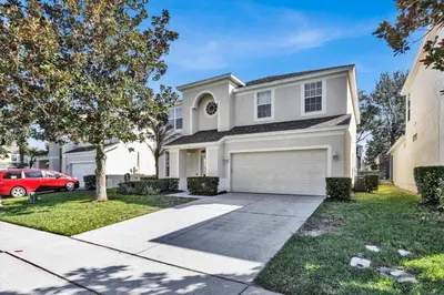 a white house with a car parked in the driveway at Orlando Villa 6472 - Family Getaway Home in Orlando