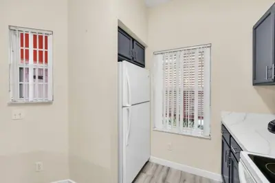a white kitchen with a refrigerator and a window at Orlando Villa 6230: A Stylish Family Retreat Near Disney in Kissimmee