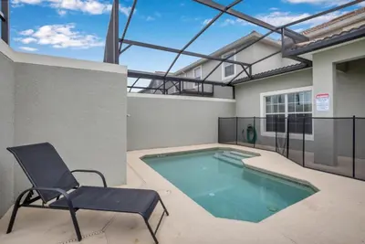 a house with a swimming pool and a chair at Orlando Villa 6243: The Best Orlando Getaway at Storey Lake in Kissimmee