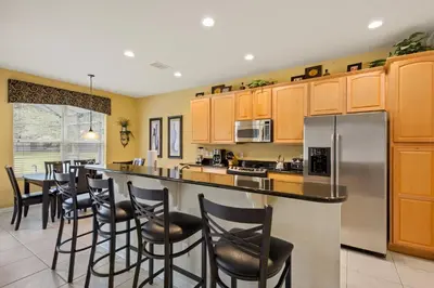 a kitchen with wooden cabinets and a bar with stools at Luxury Villa with Pool on Windsor Hills Resort Orlando Villa 5390 in Orlando