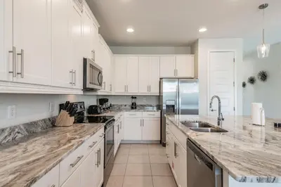 a kitchen with white cabinets and marble counter tops at Rent the Perfect 5 Bedroom Villa Encore Resort Villa 6416 in Orlando