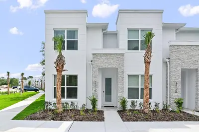 a white house with palm trees in front of it at New Luxury Dream Vacation Home With Gym, 70 inch TV, Private Pool, 4 Bedrooms, 3 Full Baths, High Speed WiFi in Orlando