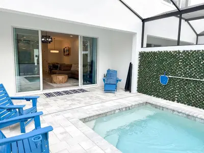 a swimming pool with two blue chairs and a house at TR1461SL - 4 bedrooms pool home - 10 guests in Orlando
