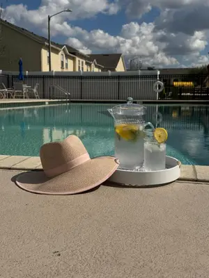 a hat and a drink on a tray next to a swimming pool at Family stay Near Disney in Kissimmee