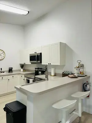 a kitchen with white cabinets and a counter with stools at Family stay Near Disney in Kissimmee