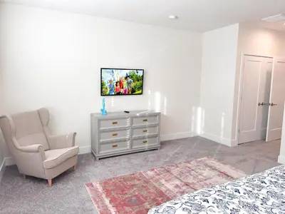 a bedroom with a chair and a tv on a wall at TR1399 – 4BR - 8 guests in Orlando