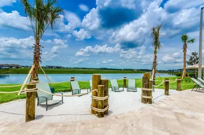 a patio with chairs and palm trees next to a lake at Beautiful 3bed 2bath Condo close to Disney Parks 344 in Kissimmee