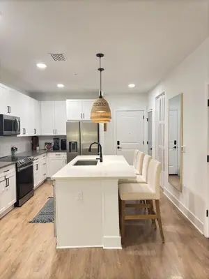a kitchen with white cabinets and a kitchen island with chairs at Modern 1 bedroom Apartment and Den in Orlando in Orlando