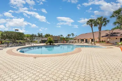 a large swimming pool with chairs and palm trees at Family Home w/ Pool & Water Views, Near Disney in Kissimmee