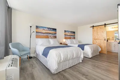 a bedroom with two beds and a blue chair at Charming Suite: Smart TV, Modern Amenities & Pool Access in Kissimmee