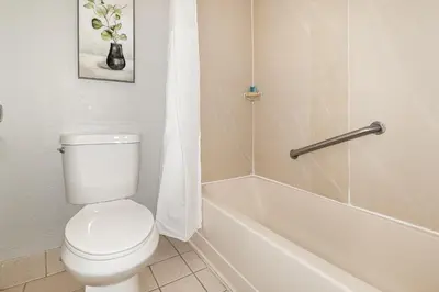 a bathroom with a toilet and a bath tub at Charming Suite: Smart TV, Modern Amenities & Pool Access in Kissimmee