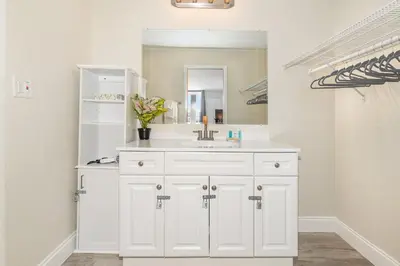 a white bathroom with a sink and a mirror at Charming Suite: Smart TV, Modern Amenities & Pool Access in Kissimmee