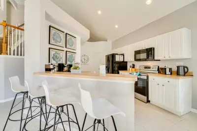 a kitchen with white stools and a counter top at 3 Mi to Disney Family-Friendly Home! in Orlando