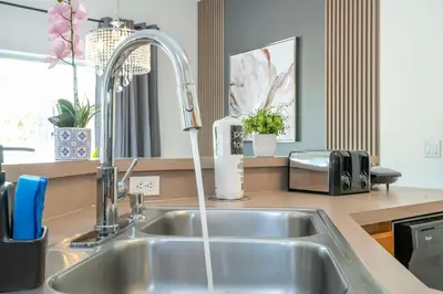 a kitchen sink with a faucet with water coming out at 4 bedrooms close to Disney in Kissimmee