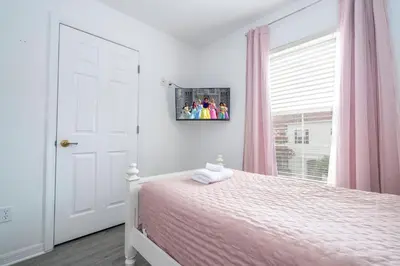 a bedroom with a bed and a window with pink curtains at 4 bedrooms close to Disney in Kissimmee