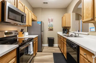 a kitchen with wooden cabinets and a stainless steel refrigerator at Stunning 2 Bedroom Retreat in Orlando6496 in Orlando