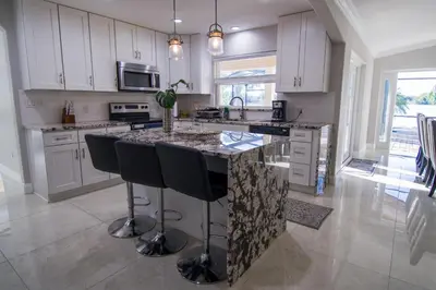 a kitchen with white cabinets and a island with bar stools at Lakefront and Pool 4bed Orlando House Near Downtown 20 minutes from Attractions in Orlando