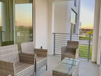 a balcony with wicker chairs and a glass table at Brand New Luxury 2bd 2 bath Condo Home 270 in Kissimmee