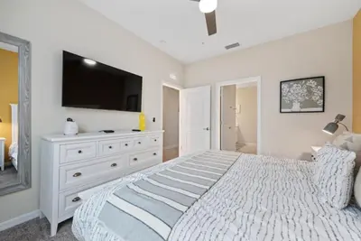 a bedroom with a large bed with a tv on the wall at Luxury 2bd 2 bath Condo Home 254 in Kissimmee